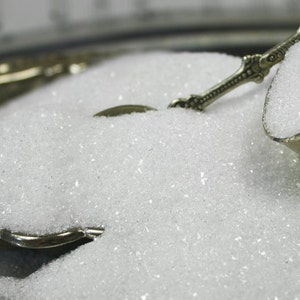 Peut inclure: Gros plan sur une cuillère en argent remplie de paillettes blanches irisées. Les paillettes sont empilées en hauteur dans la cuillère et débordent.