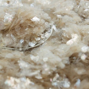 May include: Close-up of a pile of white mica flakes, a natural mineral with a pearly sheen.