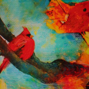 May include: A watercolor painting of two red cardinals perched on a branch. The cardinals are painted in a realistic style, with detailed feathers and bright colors. The background is a vibrant blue and green, with hints of yellow and orange.