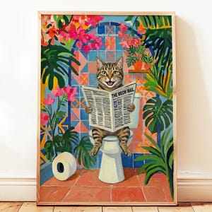 Op de afbeelding: Een ingelijste kunstdruk toont een tabby kat op een toilet, lezend een krant getiteld "The Meow Mail". Het kunstwerk toont een kleurrijke badkamer scène met tropische planten en roze bloemen, wat een grillige en humoristische esthetiek creëert.