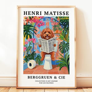May include: A framed art print featuring a dog reading a newspaper on a toilet. The print has the text "HENRI MATISSE" at the top and "BERGGRUEN & CIE" at the bottom. The dog is brown, and the background includes plants and colorful tiles.