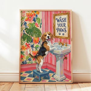 Könnte beinhalten: Ein gerahmter Kunstdruck, der einen Beagle zeigt, der auf einem blauen Tritthocker steht und seine Pfoten in einem weißen Waschbecken wäscht. Der Hintergrund zeigt florale Tapeten und rosa Streifen sowie ein goldenes Schild mit der Aufschrift Wash Your Paws.