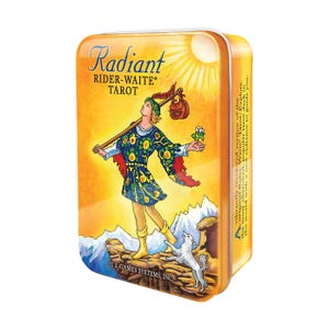 May include: A rectangular metal tin featuring the "Radiant Rider-Waite Tarot" deck. The artwork depicts a figure with a staff, a dog, and mountains against a yellow and orange background. The text on the tin reads "Radiant Rider-Waite Tarot".
