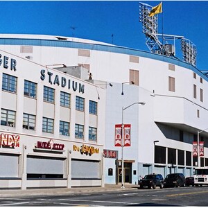 May include: An exterior view of a white building with blue trim. The building has a large sign that reads "Tiger Stadium". There are several smaller signs below the large sign, including "Candy" and "Jim's Ice Cream". There are also several banners hanging from the building, including one that reads "Will Call".