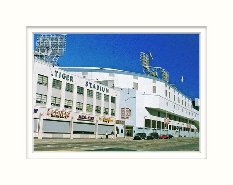 May include: An exterior view of Tiger Stadium, a white building with a blue sky in the background. The stadium has a large sign that reads "Tiger Stadium".