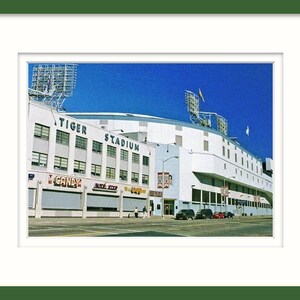 May include: A vintage photograph of Tiger Stadium in Detroit, Michigan. The stadium is white with a blue sky in the background. The words "Tiger Stadium" are visible on the side of the building.