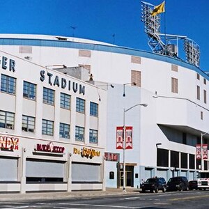 May include: An exterior view of Tiger Stadium, a large white building with blue trim and the words "Tiger Stadium" in blue lettering. The stadium has many windows and a large sign that says "Candy" in red and white lettering.