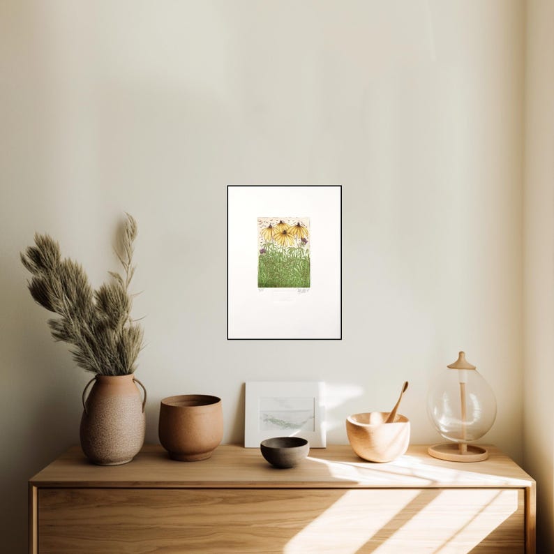 May include: A framed print of a botanical illustration featuring yellow flowers with brown centres and green leaves. The print is set against a white background.