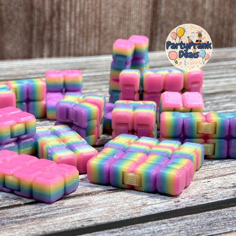 K&ouml;nnte beinhalten: Eine Sammlung farbenfroher, regenbogenfarbener Zappelspielzeuge. Die Spielzeuge bestehen aus kleinen, ineinandergreifenden Bl&ouml;cken in Rosa-, Gelb-, Lila- und Blaut&ouml;nen. Die Spielzeuge sind auf einer Holzoberfl&auml;che angeordnet.