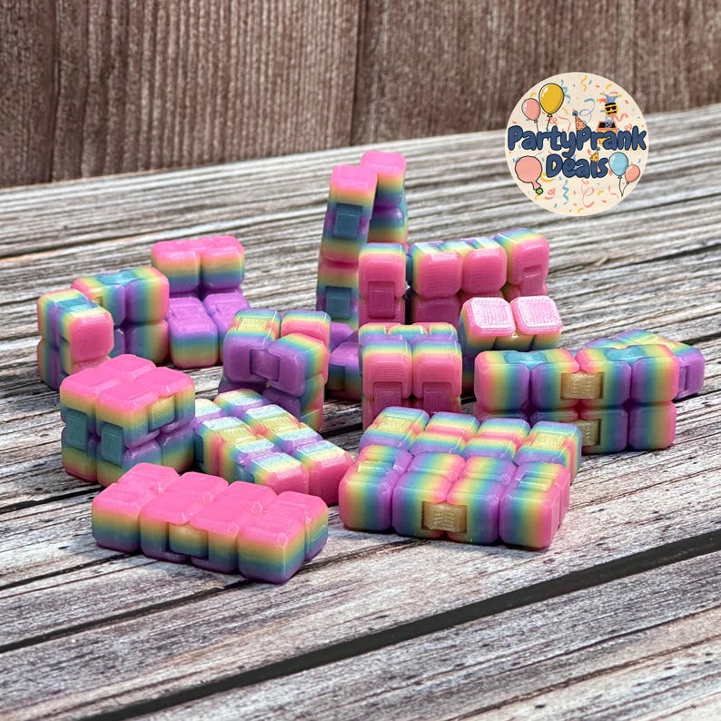 K&ouml;nnte beinhalten: Eine Sammlung farbenfroher, regenbogenfarbener Zappelspielzeuge in verschiedenen Formen. Die Spielzeuge sind haupts&auml;chlich rosa, lila, gelb und blau, angeordnet auf einer Holzoberfl&auml;che. Die Spielzeuge sind zum Manipulieren und Spielen konzipiert.