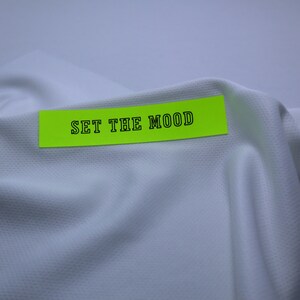 May include: A bright yellow sticky note with the text "SET THE MOOD" written in black on a white fabric background.
