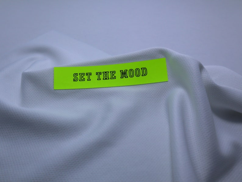 May include: A bright yellow sticky note with the text "SET THE MOOD" written in black on a white fabric background.