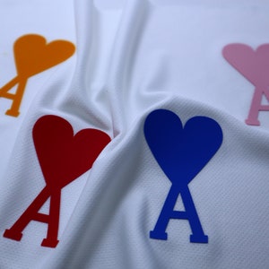May include: Four fabric hearts with the letter 'A' in the center, in orange, pink, red, and blue.