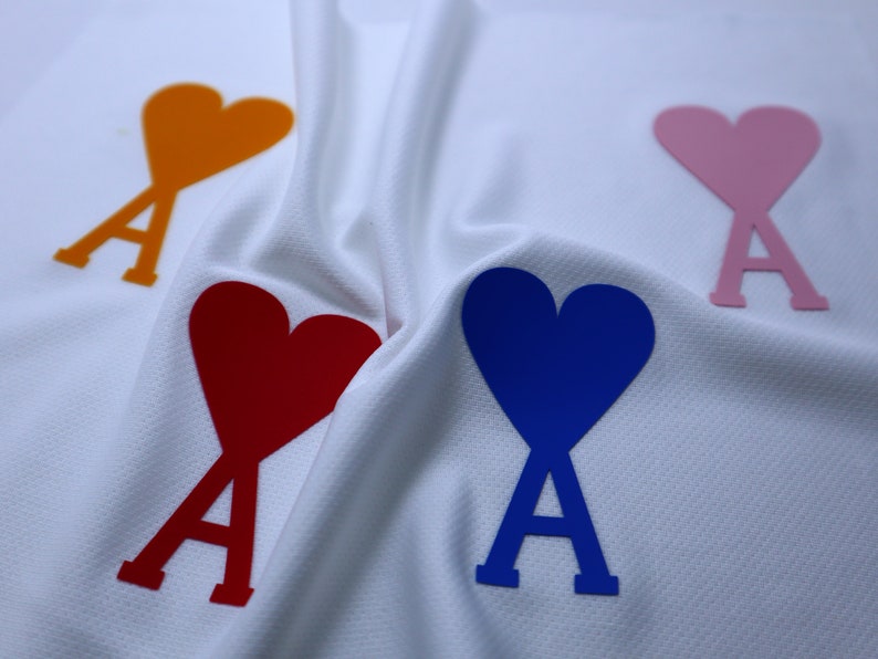 May include: Four fabric hearts with the letter 'A' in the center, in orange, pink, red, and blue.