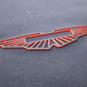 May include: A red winged logo on a dark blue fabric background.