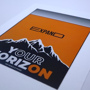 May include: Orange and black graphic print with the text "EXPAND YOUR HORIZON" and "THE WORLD IS YOURS". The graphic features a mountain range.