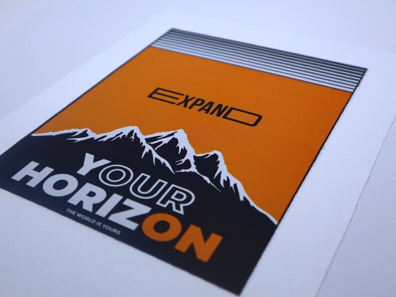 May include: Orange and black graphic print with the text "EXPAND YOUR HORIZON" and "THE WORLD IS YOURS". The graphic features a mountain range.