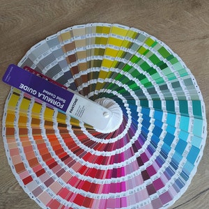 Puede incluir: Un abanico de gu&iacute;a de color con un dise&ntilde;o en espiral. El abanico est&aacute; abierto para revelar una gama de colores, incluyendo rojo, naranja, amarillo, verde, azul, morado y gris. El abanico est&aacute; etiquetado como "Pantone Solid Coated Formula Guide".