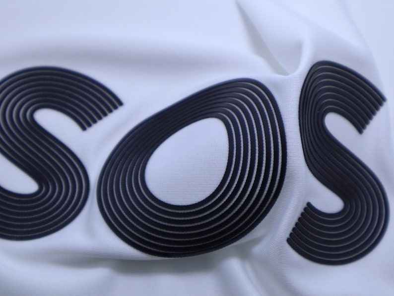 May include: White fabric with the word "SOS" printed in black, with each letter made up of multiple overlapping lines.