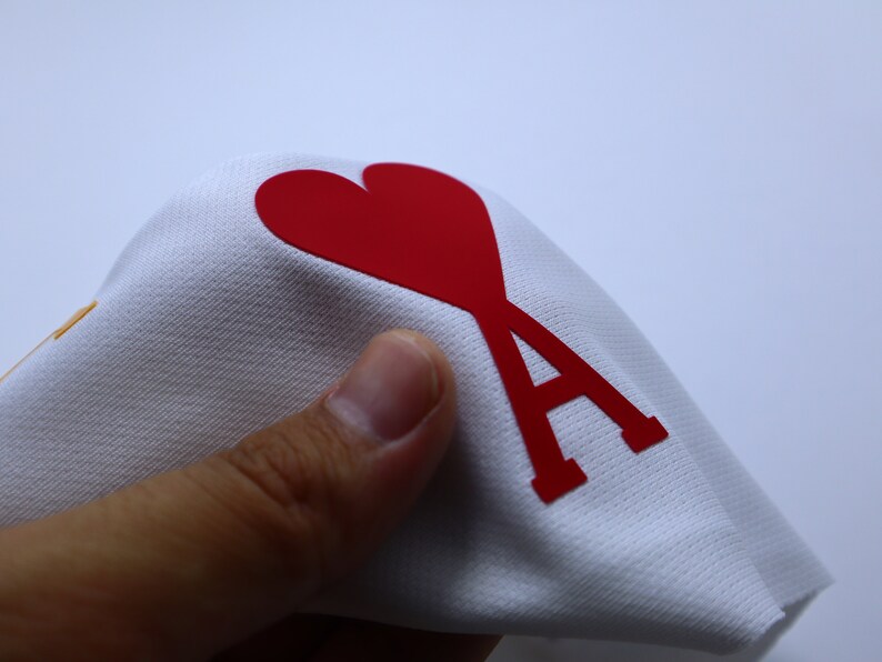 May include: White fabric with a red heart and the letter A printed on it.