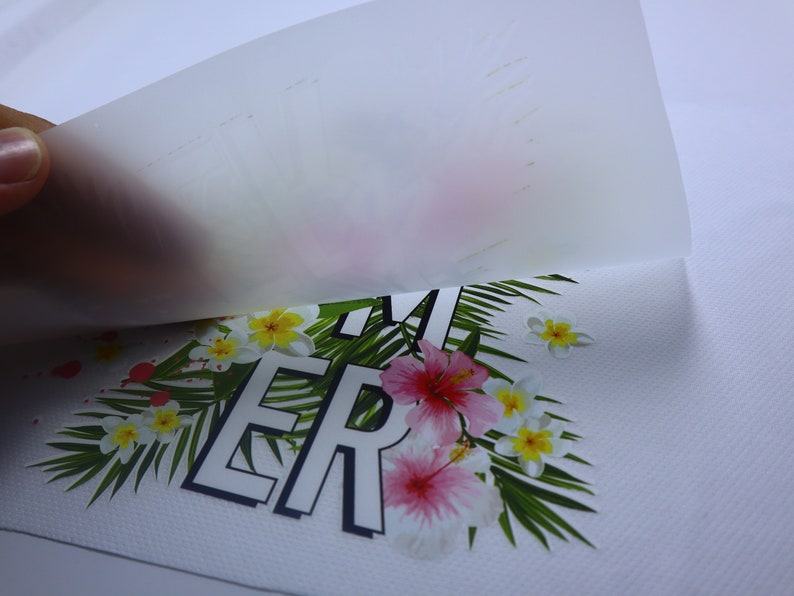 May include: A white t-shirt with a tropical print featuring pink and yellow flowers, green leaves, and the word "SUMMER" in black letters.