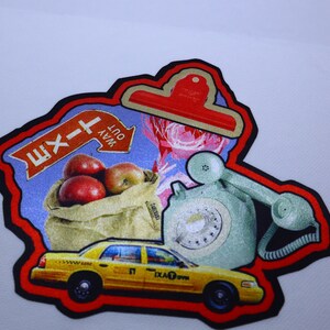 Peut inclure: Un patch color&eacute; avec un panneau de sortie rouge, blanc et bleu, un sac de pommes rouges, un t&eacute;l&eacute;phone rotatif vert vintage et un taxi jaune. Le patch est entour&eacute; d'une bordure noire et d'un contour rouge.
