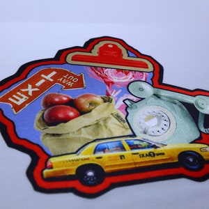 Peut inclure: Un patch rouge, noir et blanc avec un taxi jaune, une pomme rouge dans un sac en papier brun, un panneau bleu avec le texte "WAY OUT" et le texte cyrillique "Ш-1", et un t&eacute;l&eacute;phone &agrave; cadran vert.