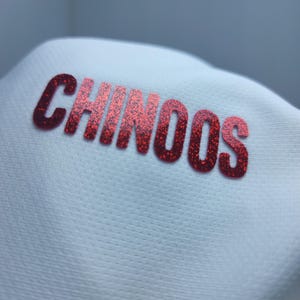 May include: White hat with the word "CHINOOS" in red glitter lettering.