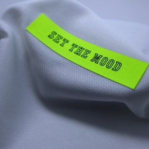 May include: A white fabric with a bright green sticky note that says "SET THE MOOD" in black text.