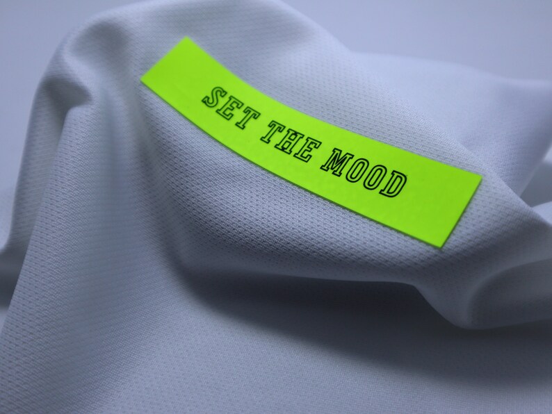 May include: A white fabric with a bright green sticky note that says "SET THE MOOD" in black text.