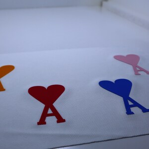 May include: Four felt hearts with the letter 'A' inside, each heart is a different color: orange, red, blue, and pink.