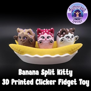 May include: Three 3D printed cat figurines in a banana split boat. The cats are brown, pink, and white with purple and red accents. The boat is yellow and white. The text "Banana Split Kitty 3D Printed Clicker Fidget Toy" is below the boat.