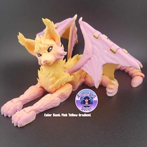 May include: A hand-painted, pink and yellow gradient, dragon-like creature with wings. The creature is lying down with its wings spread out. The creature has a long tail and a pointed snout.