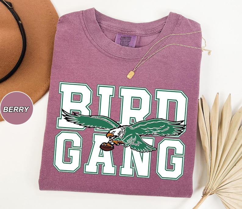 May include: A purple t-shirt with a white and green graphic of an eagle with the text "BIRD GANG" on it.