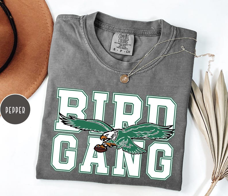 May include: A gray t-shirt with a white graphic of a green eagle with the text "BIRD GANG" in white.