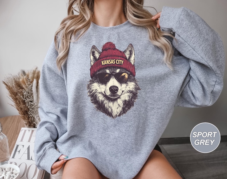 May include: A gray sweatshirt with a graphic of a wolf wearing a red beanie with the text "Kansas City".