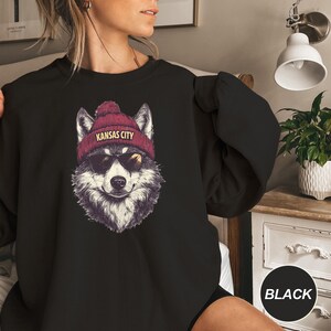May include: Black sweatshirt with a graphic of a wolf wearing a red beanie with the text "Kansas City".