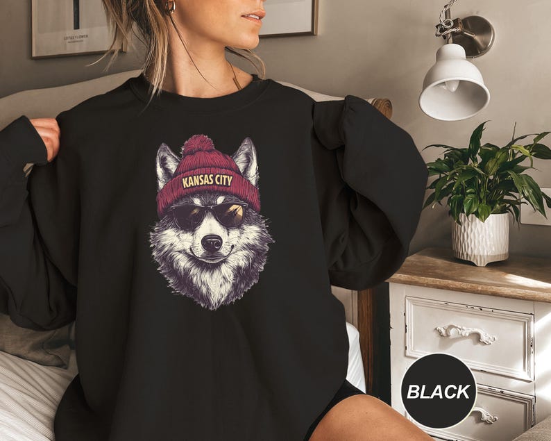 May include: Black sweatshirt with a graphic of a wolf wearing a red beanie with the text "Kansas City".