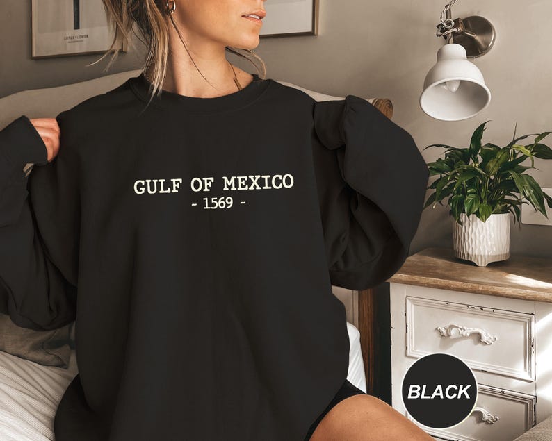 Op de afbeelding: Zwart sweatshirt met de witte tekst "GULF OF MEXICO - 1569 -". De crew neck sweatshirt is effen zwart van kleur. De tekst is gecentreerd op de borst.