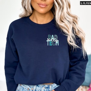 May include: A navy blue sweatshirt with a graphic design that says "Rad Tech" in a gradient of blue and green colors.