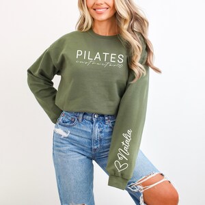 May include: A green sweatshirt with the text "PILATES instructor" and a heart symbol. The left sleeve has the name "Natalia" written on it.