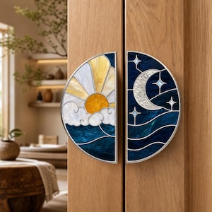May include: Two semi-circular door handles featuring stained glass designs. The left handle depicts a yellow sun with white clouds over blue waves. The right handle shows a silver crescent moon and stars against a dark blue night sky.