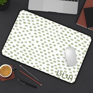 May include: A white mousepad with a black border and a pattern of green watercolor dots. A white computer mouse sits on the pad. The initials "BDR" are printed in the lower right corner.