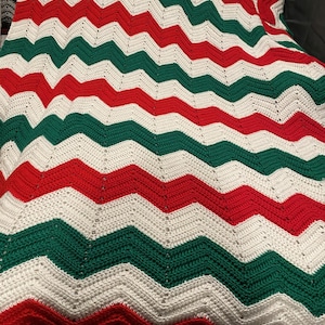 May include: A crocheted blanket with a chevron pattern in red, white, and green.