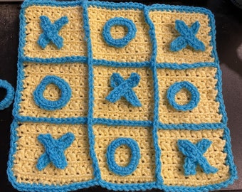 May include: A crocheted tic-tac-toe game board with blue X's and yellow O's. The board is made of yellow yarn with blue trim.