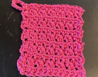 Puede incluir: Un paño de cocina de crochet rosa con un asa de bucle.