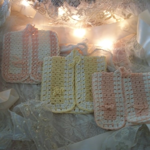 May include: Three crocheted collars in pink, yellow, and white. The collars are made with a delicate stitch and have a scalloped edge.
