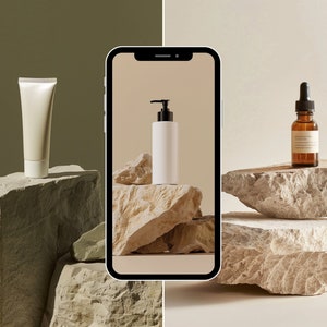 May include: A white tube of cream, a white pump bottle of lotion, and a brown glass bottle of serum are displayed on stacked light brown rocks. The products are photographed on a smartphone screen.