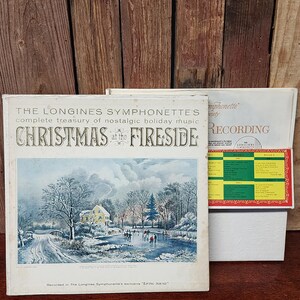 May include: A vintage record album cover featuring a snowy winter scene with a house, a frozen pond, and people ice skating. The album title is "Christmas at the Fireside" and is a complete treasury of nostalgic holiday music by The Longines Symphonette. The album is recorded in the Longines Symphonette's exclusive "Living Sound".