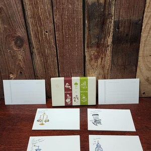 May include: A set of vintage postcards and a box with the words "Post a Note". The postcards have illustrations of a scale, rocking chair, coffee grinder, and a decorative vase. The box has a red, white, and green design.